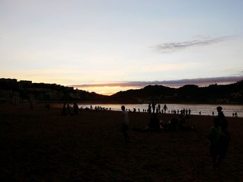 Tourists at beach during sunset