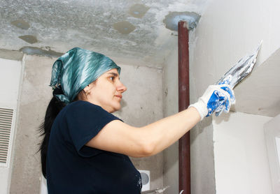 Woman plastering wall at home