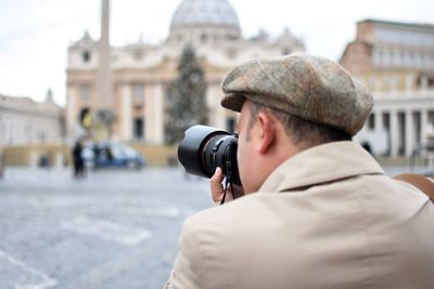 Close-up of man photographing through camera in city