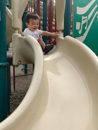 Cute boy playing on slide at playground