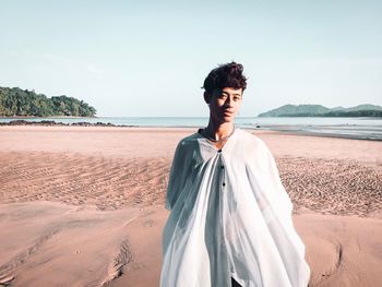 Young man standing on beach against sky