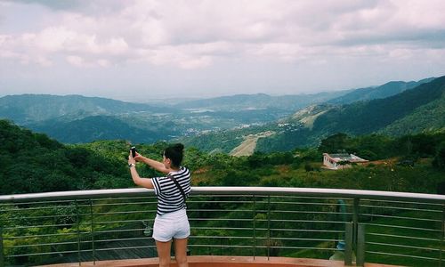 Silhouette of woman standing on mountain against sky