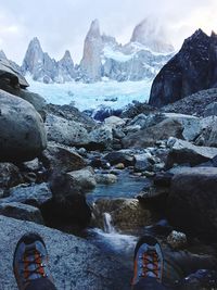 Low section of man by stream against mountains at torres del paine national park