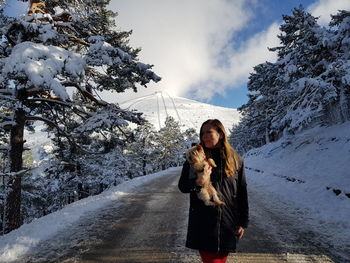 Full length of woman with dog in snow