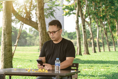 Man using phone while sitting at table outdoors