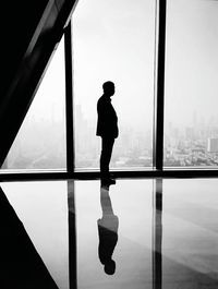 Silhouette of man looking through window