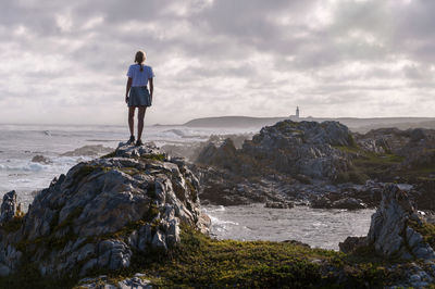 Woman standing on rock  against sky