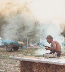 Shirtless senior man making straw basket