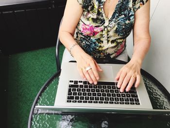 Midsection of woman using mobile phone while sitting on table