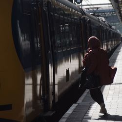 Rear view of woman walking on railroad station platform