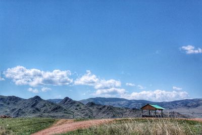 Scenic view of field and mountains against blue sky