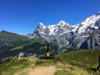 Woman on snowcapped mountain against clear blue sky