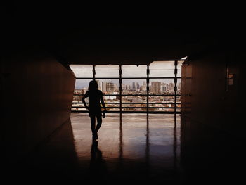 Rear view of silhouette man walking on tiled floor