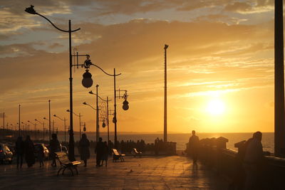 Silhouette city by sea against sky during sunset