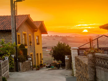 Houses by street against sky during sunset