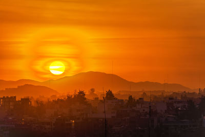 Cityscape by andes mountain against sky during sunset