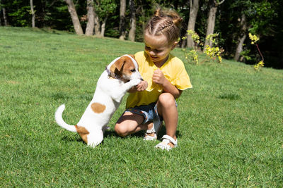 Portrait of young woman with dog on grassy field