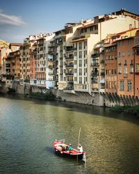 Boats in river by buildings in city