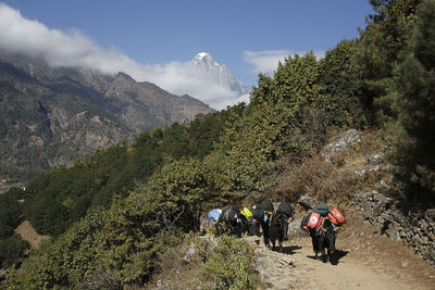 People walking on mountain against sky