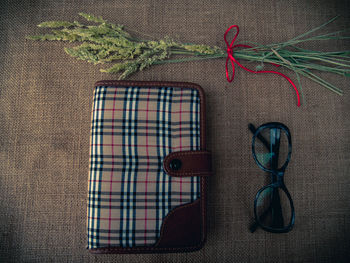 Directly above shot of diary and eyeglasses with plants on burlap