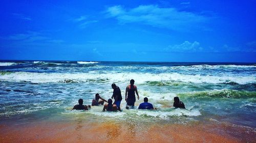 People on beach against blue sky