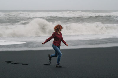 Redhead lady running along black beach scenic photography