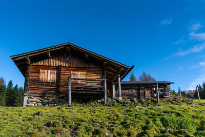 House on field against clear blue sky