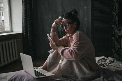 Woman holding mobile phone at home