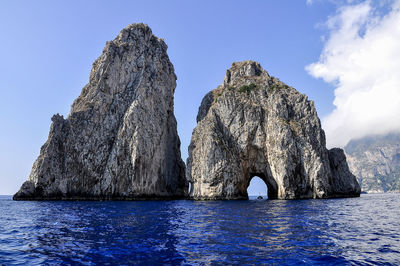 Rock formation by sea against blue sky