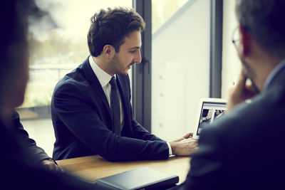 Young male financial advisor explaining strategy with laptop during meeting in law firm