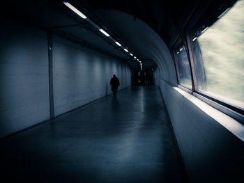 Rear view of person walking in illuminated tunnel