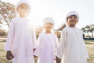 Portrait of smiling brothers wearing traditional clothing standing in park