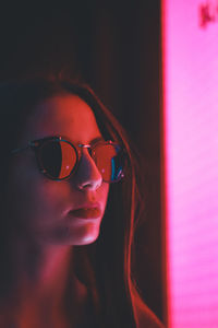 Close-up of woman wearing sunglasses in illuminated room