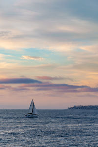 Sailboat sailing on sea against sky during sunset