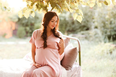 Pregnant woman sitting on bed at park