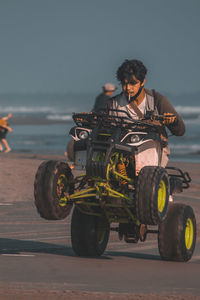 Man riding motorcycle on road against sea