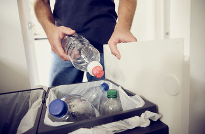 Young man recycling plastic bottles at home