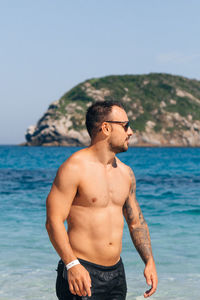 Shirtless young man walking on beach