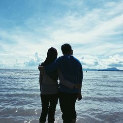 Couple looking at sea against sky