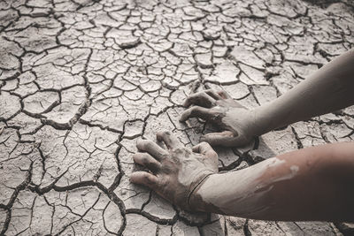 Cropped hand of women on arid land by faucet