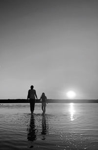 Rear view of woman walking at beach against sky