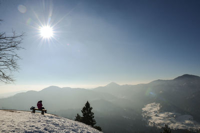 Man sitting on snowcapped mountain against clear sky