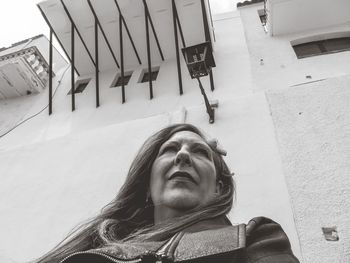 Low angle portrait of woman standing against building