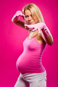 Pregnant woman standing against pink background