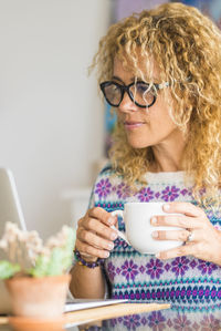 Portrait of smiling young woman holding coffee at home