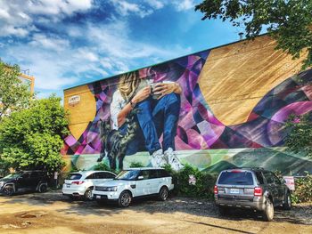 Graffiti on wall by trees against sky