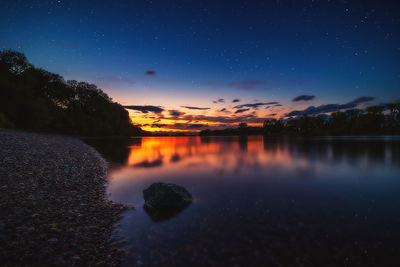 Scenic view of lake against sky at night
