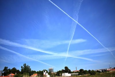 Low angle view of vapor trails against blue sky