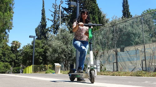 Woman riding kick scooter on road