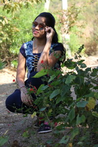 Portrait of young woman crouching on land outdoors